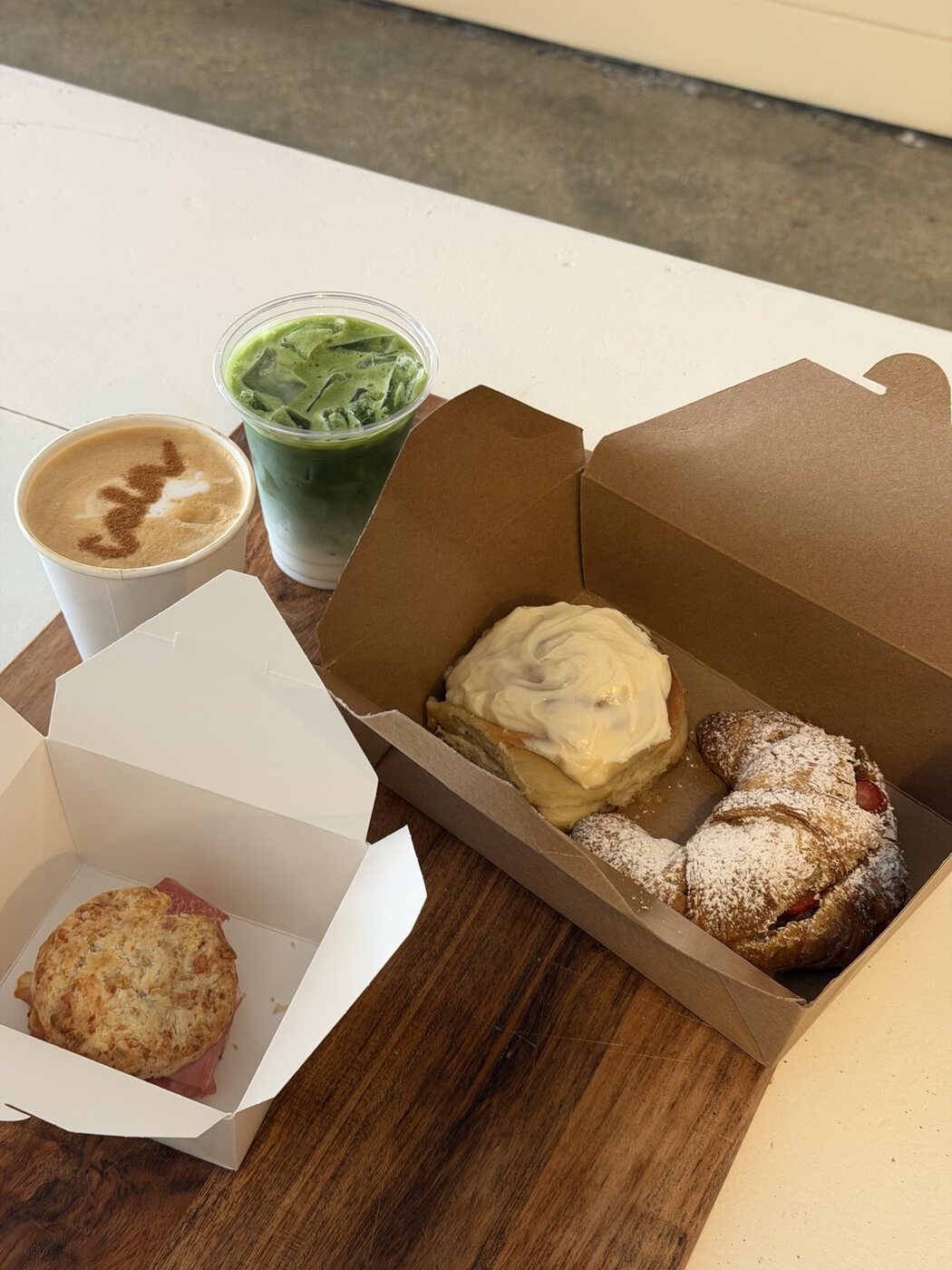 Matcha, coffee, cinnamon roll, croissant and breakfast sandwich at CALA